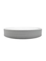 Round white ceramic plate with ribbed texture on a white background